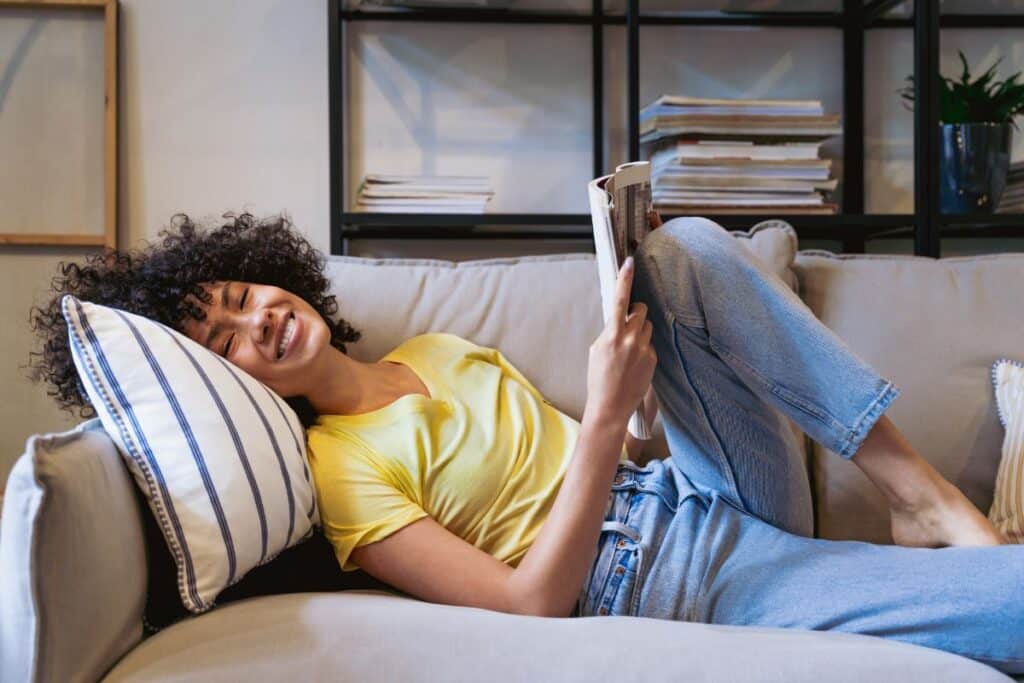 woman reading book on couch.